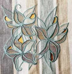 two embroidered flowers on a striped fabric with gold and blue accents, one in the center