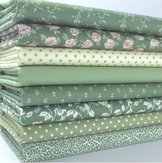 a stack of green and white fabric with polka dot designs on the bottom, along with pink flowers