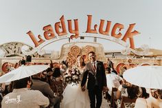 a bride and groom are standing in front of the lady luck sign at their wedding