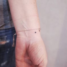 a person wearing a tiny star tattoo on their left wrist with a tassel attached to it