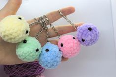 four small balls of yarn are being held by a person's hand with rings around them