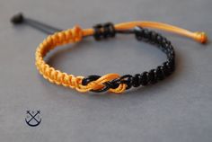 an orange and black rope bracelet on a gray surface