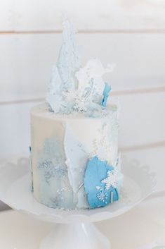 a white and blue cake with frosting on it sitting on top of a table