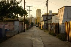 an alley way with buildings in the background and trees on both sides, at sunset