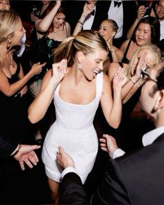 a woman in a white dress is dancing with other people at a formal event together