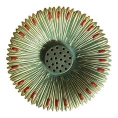 a metal object with red and green designs on it's sides, in the shape of a sunburst