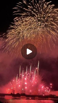 fireworks are lit up in the night sky over water and pier with boats on it