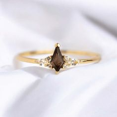 a gold ring with a brown stone and white stones on the side, sitting on a white sheet