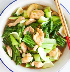 a white bowl filled with meat and veggies next to two chopsticks