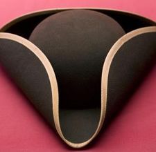 a black hat with gold trim on a pink tableclothed surface in the shape of a cone