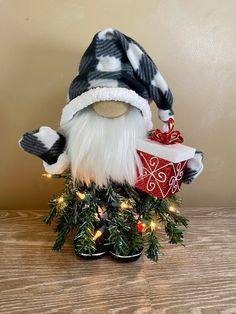 a small christmas gnome holding a present on top of a wooden table