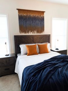 a bedroom with a bed, two windows and a painting on the wall above it