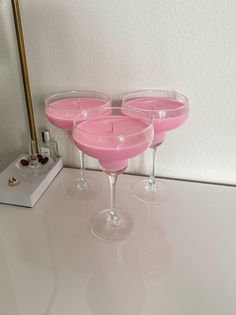 three wine glasses sitting on top of a table next to a candle and a mirror