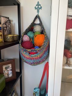 there is a crochet bag hanging on the wall with balls of yarn in it