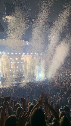 a large crowd at a concert with confetti thrown in the air and on stage