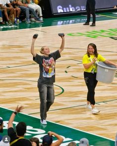 two women are holding their hands up in the air as they walk on a basketball court