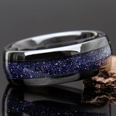 a close up of a ring with blue glitter on it and a piece of wood next to it