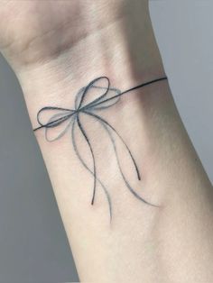 a wrist tattoo with a bow on it