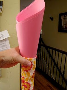 a person is holding a pink vase in their hand and some papers on the wall