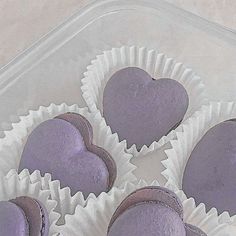 purple heart shaped pastries sitting in a plastic container on top of a white table