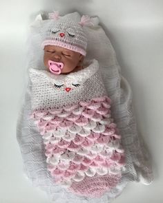 a newborn baby wrapped in a blanket and wearing a pink pacifier on it's head