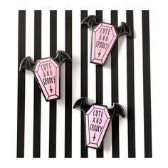 three pins with bats on them sitting next to black and white striped wallpaper that says out and about