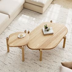 two wooden tables sitting on top of a white carpeted floor next to a couch