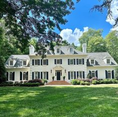 a large white house sitting in the middle of a lush green field