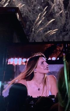 a woman is smiling while standing in front of fireworks