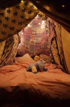 a stuffed animal sitting on top of a bed in a tent