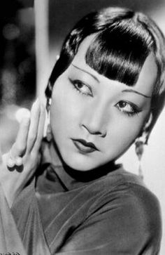 an old photo of a woman with short hair and wearing a turtle neck top, holding her hand up to her ear