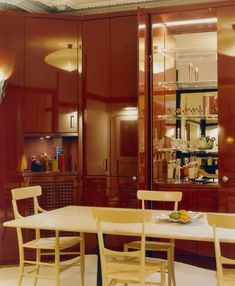 a dining room table and chairs in front of some cupboards with lights on them