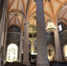 the inside of a church with columns and chandeliers