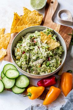 a bowl filled with guacamole surrounded by sliced cucumbers and peppers