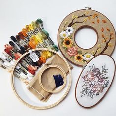 three embroidery kits are sitting next to each other on a white surface, one has a flower design and the other has an embroidered hoop