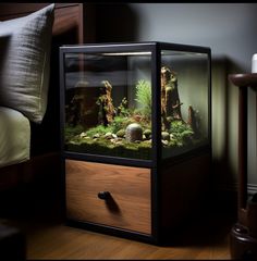 an aquarium with rocks and plants in it on a wooden table next to a bed