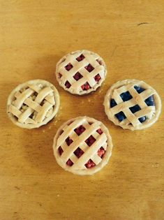 four small pies with red, white and blue toppings on a wooden table