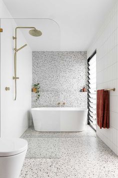 a white bath tub sitting in a bathroom next to a shower head and hand held faucet