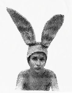 a black and white photo of a person wearing a bunny ears hat with his face partially obscured by the background