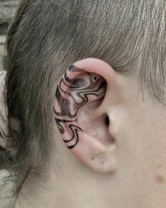 a close up of a person's ear with tattoos on it