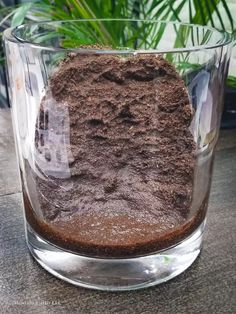 a glass filled with dirt sitting on top of a table