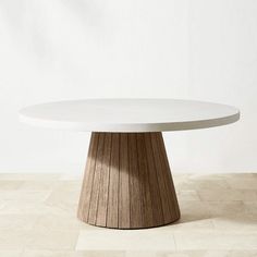 a round white table sitting on top of a tile floor next to a wall with a wooden base