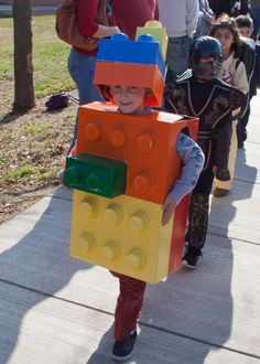 a young child in lego costume walking down the sidewalk