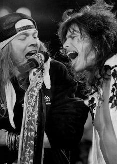 two women singing into microphones while wearing hats and scarves