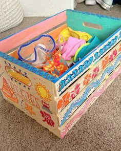 a wooden box filled with lots of colorful clothing and glasses on top of carpeted floor