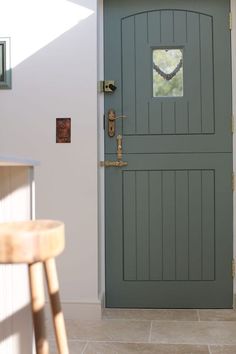 the front door to a house with a wooden stool in front of it and a clock on the wall