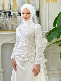 a woman in a white dress and veil posing for the camera with her hands on her hips