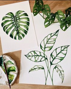 two paintings of green leaves on white paper next to a plate with paintbrushes