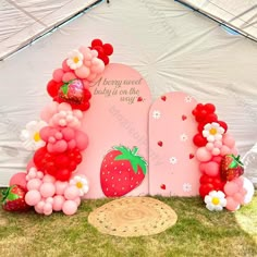 a strawberry themed baby shower is set up in the grass with balloons and flowers on it