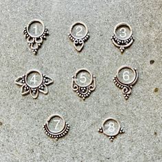 six pairs of earrings with numbers on them sitting next to each other in front of a cement surface